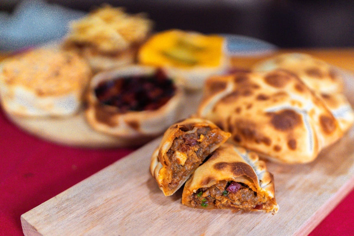 Empanadas de carne cortadas al medio sobre tabla de madera