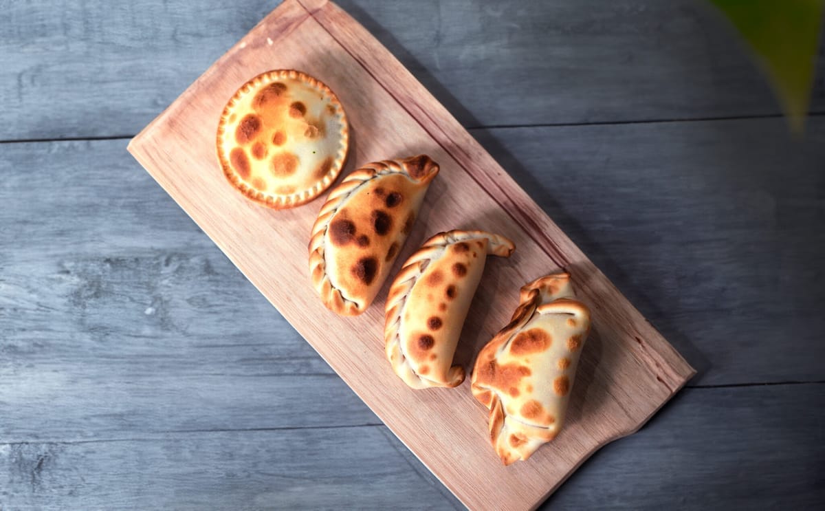Tabla de madera con empanadas recién horneadas de Jaque